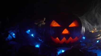 Wall Mural - Halloween, pumpkins on the leaves. red luminous lights inside them, smoke from the side, is illuminated by blue neon light. Witchcraft and magic.