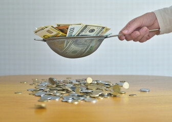 sift money through a sieve. coins fall out of the sieve