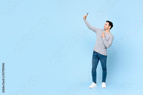 Fotomural Full body portrait of young handsome man taking selfie on mobile phone isolated