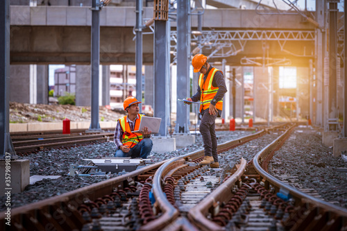 Fotomural Engineer under inspection and checking construction process railway switch and checking work on railroad station