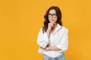 puzzled young brunette business woman in white shirt glasses isolated on yellow background. achievem