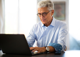 older businessman working from home with laptop computer
