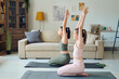 © pressmaster - Mother and teenage daughter sitting on exercise mats and practicing yoga at home