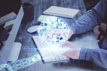 Crypto currency theme hologram with businessman working on computer on background. Concept of blockchain. Multi exposure.