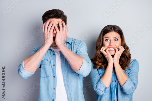 Closeup photo pretty lady handsome guy shocked couple open mouth arms cheeks cover eyes listen news corona virus quarantine wear casual denim shirts isolated grey color background