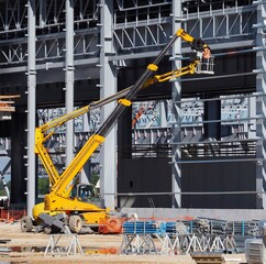 A telescopic handler and an aerial platform at work on the frame of a new building under construction