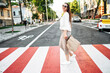 © Vadim Pastuh - Walk around the city. Beautiful young woman is walking on a pedestrian crossing with a paper shopping bag and laughing. Side view