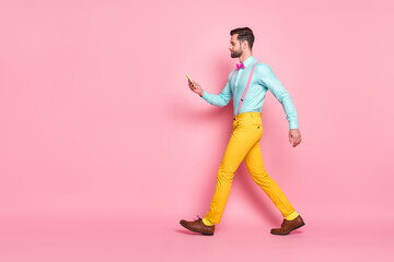 Poster - Full size profile side photo of serious focused guy blogger go walk copyspace use cellphone read social network news post wear trousers shoes shirt isolated pastel color background