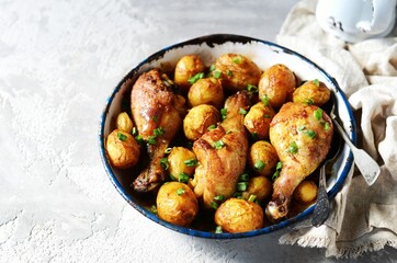 Wall Mural - Baked chicken legs with young potatoes in a baking dish on a gray background