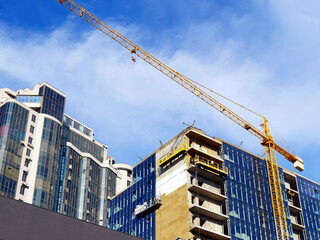 Construction site. Construction of modern high-rise luxury residential buildings. Large tower crane near the building under construction.