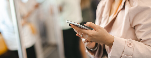 Poster - close up hand woman holding mobile phone or smartphone in subway train transit system public.