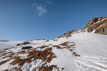 Wall Mural - Snowy hill with rocks and blue sky in alpine on winter