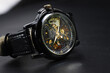 © ijp2726 - Black automatic self winding wristwatch with transparent sekeleton dial design on black leather background