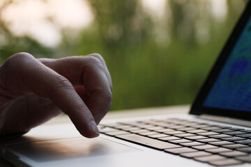 man, businessman, programmer, working in the evening at a laptop on the balcony of his house, hands 