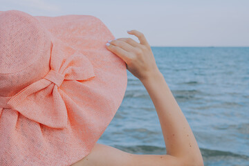 girl hold hat toward the sea 