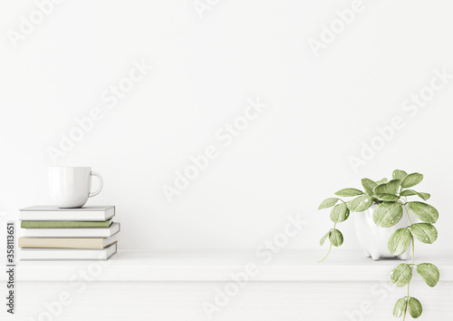 Fotografía Interior wall mockup with green plant in pot and pile of books with cup on empty white background with free space on center