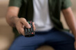 © Chanakon - Close up hand holding remote control and watching TV