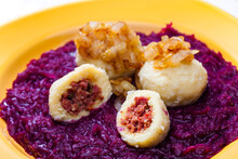 potato dumplings filled with smoked meat with fried onion on red cabbage