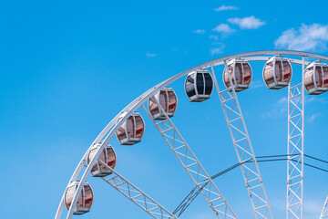 Modern white Ferris wheel against a blue sky with clouds, Attraction for children and tourists, top city view in Krakow, Poland.