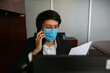 © Leo Cerz - Stock photo of a man sitting talking on the phone, he is wearing a protective mask for virus prevention. He is in an office working