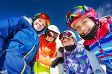 Group Of Kids In Ski Outfit Mask Ang Helmets Look Down Standing Together Over Blue Sky