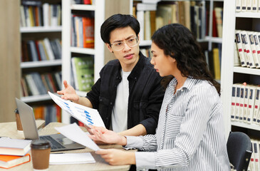 Wall Mural - Two students discussing charts and diagrams in library