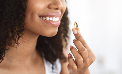 Wall Mural - Beauty Supplement. Smiling Black Girl Taking Biotin Vitamin Capsule For Healthy Skin