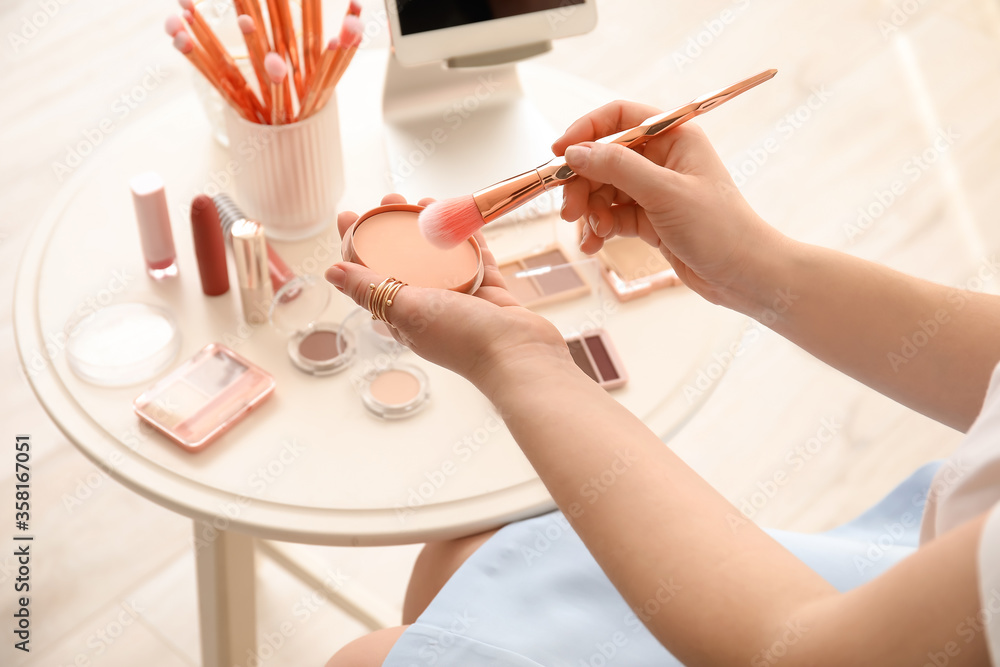 Makeup artist with decorative cosmetics sitting at table