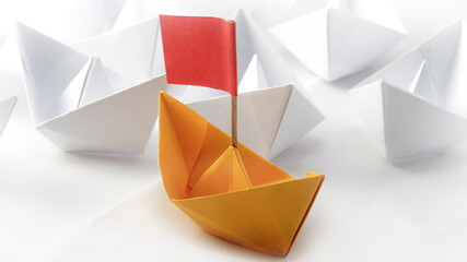 red flag yellow origami paper boat (ship )leading among white. white background. success and leaders