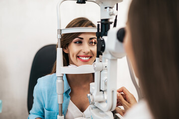 Female optometrist checking patient's vision at eye clinic. Healthcare and medical concept.