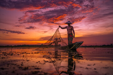 life of Asia two fisherman Silhouette using nets to catching fish at the lake in the sunset.