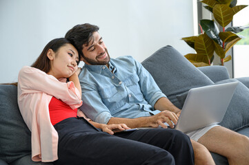 Happy and relax  lifestyle of young couple lover wearing casual dress together working on sofa with  laptop notebook computer in living room at home.