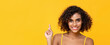 © Atstock Productions - Happy smiling curly hair beautiful woman pointing hand up to copy space isolated on yellow banner background