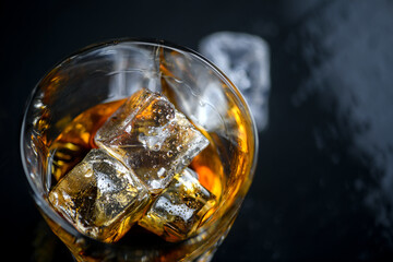 Wall Mural - Glass of whiskey with cube ice on black background