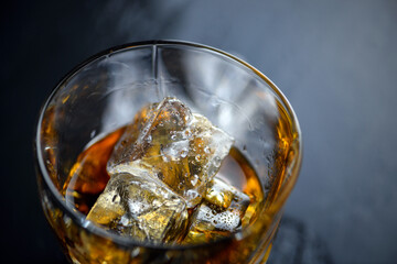 Wall Mural - Glass of whiskey with cube ice on black background