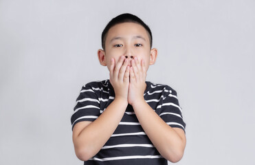 Asian boys studio portrait on gray background shocked covering mouth with hands for mistake. Secret concept.