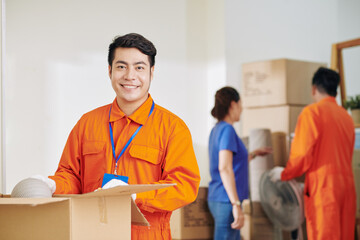 Wall Mural - Portrait of young adult Asian man working in modern delivery service together with his colleague helping woman to move house