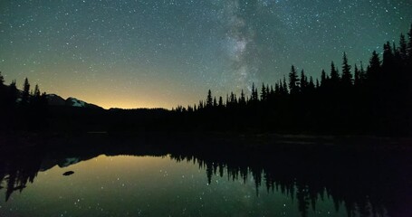 Wall Mural - Lockdown shot of silhouette trees against stars with reflection on lake - Panorama Ridge, Canada