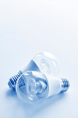 Two transparent LED light bulbs in monochrome blue. Energy saving concept with copy space. Vertical image.