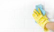 Hand and glove cleaning the bathroom tiles.