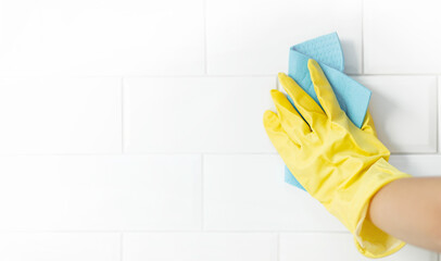 Hand and glove cleaning the bathroom tiles.