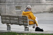 eine ältere Frau  - Rentnerin sitzt allein und einsam auf einer Bank