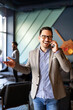 © NDABCREATIVITY - Business, people and office concept. Happy young businessman talking on phone in office