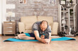 © DC Studio - Athletic man stretching out before workout on yoga mat in home during global pandemic.