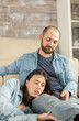 © DC Studio - Husband looking at wife while resting together on living room rug.
