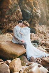 Wall Mural - Beautiful wedding couple standing between rocks in love