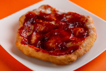 Wall Mural - Traditional Transylvanian hungarian pastry, deep fried dough langos with jam close up on white plate