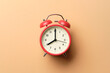 © samrit - Red vintage alarm clock on pastel orange paper background.