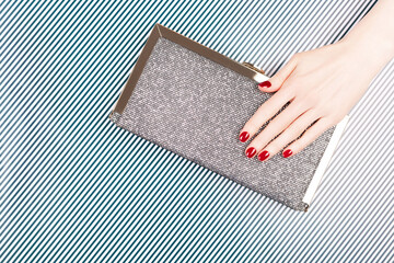 Wall Mural - Luxury manicure and nail care concept. A woman hand with perfect red polish nails with a glitter cluth on black and white striped background. Classic and elegant design. Flat-lay, top view.