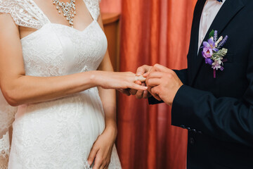 Wall Mural - groom puts a gold wedding ring on the bride's finger